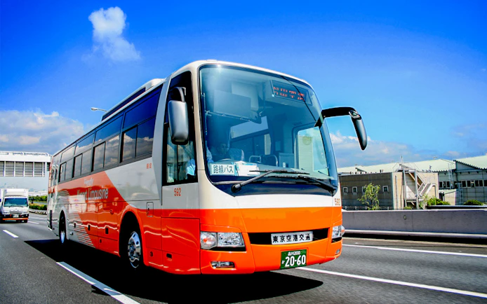 Tokyo Airport Limousine Bus driving on highway with cityscape background.