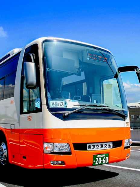 Tokyo Airport Limousine Bus driving on highway with cityscape background.