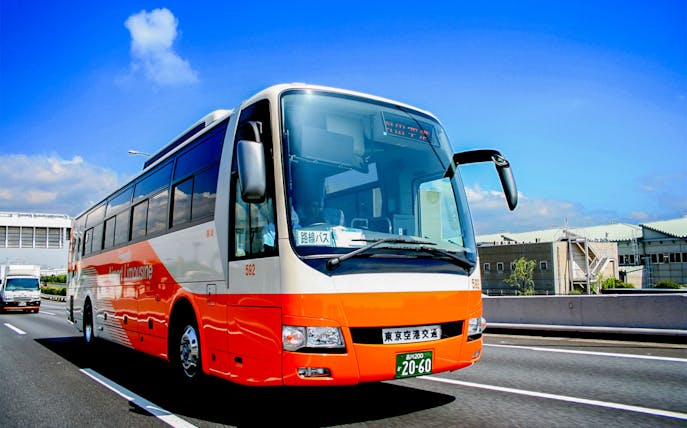 Tokyo Airport Limousine Bus driving on highway with cityscape background.