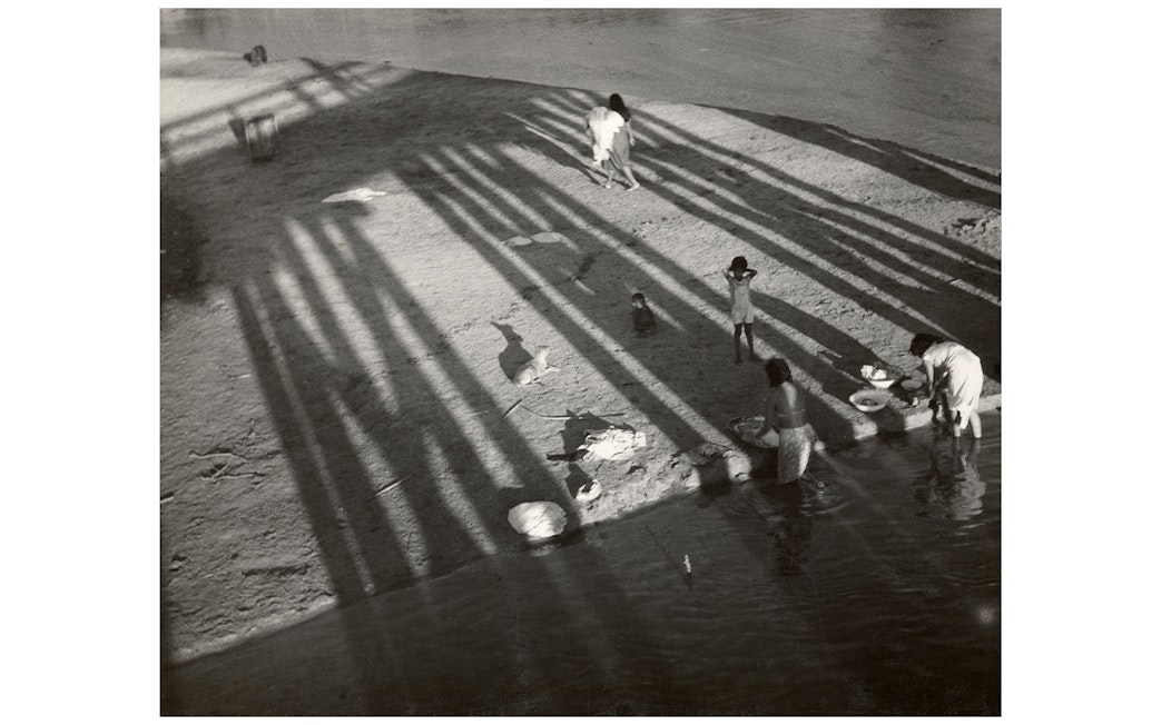 Women washing clothes by a river, shadows cast by a bridge, part of the National Gallery of Victoria exhibition.