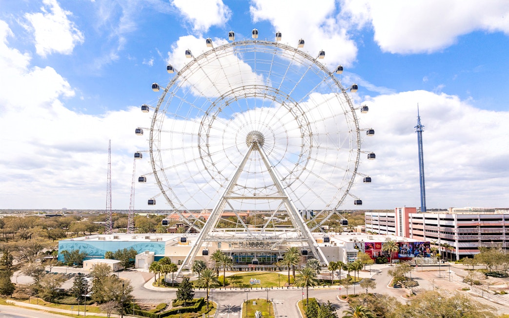 Ferris wheel at ICON Park, Orlando with surrounding attractions and blue sky.