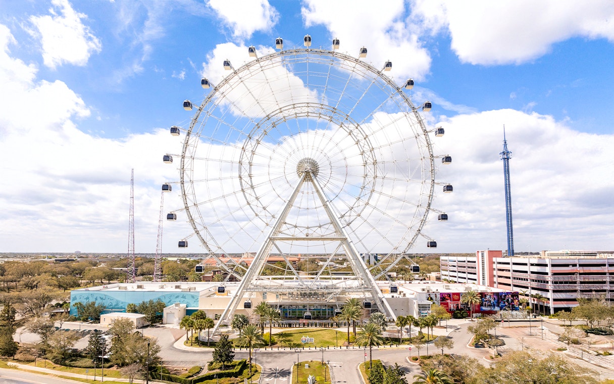 Ferris wheel at ICON Park, Orlando with surrounding attractions and blue sky.