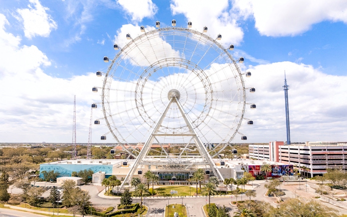 Ferris wheel at ICON Park, Orlando with surrounding attractions and blue sky.