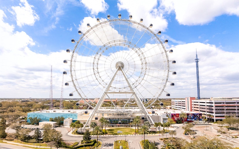 Ferris wheel at ICON Park, Orlando with surrounding attractions and blue sky.