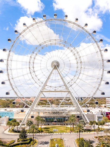 Ferris wheel at ICON Park, Orlando with surrounding attractions and blue sky.