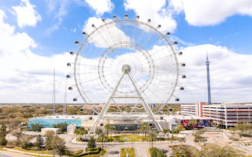Ferris wheel at ICON Park, Orlando with surrounding attractions and blue sky.