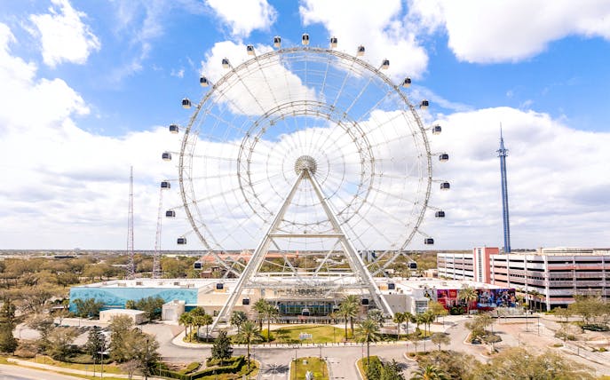 Ferris wheel at ICON Park, Orlando with surrounding attractions and blue sky.