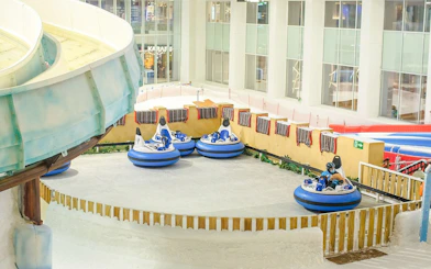 Bumper cars on snow at Snow Dunes Theme Park indoor attraction.