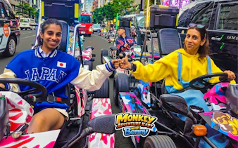 Go-kart riders fist bumping on Dotonbori street during Shinsaibashi 75-min experience.