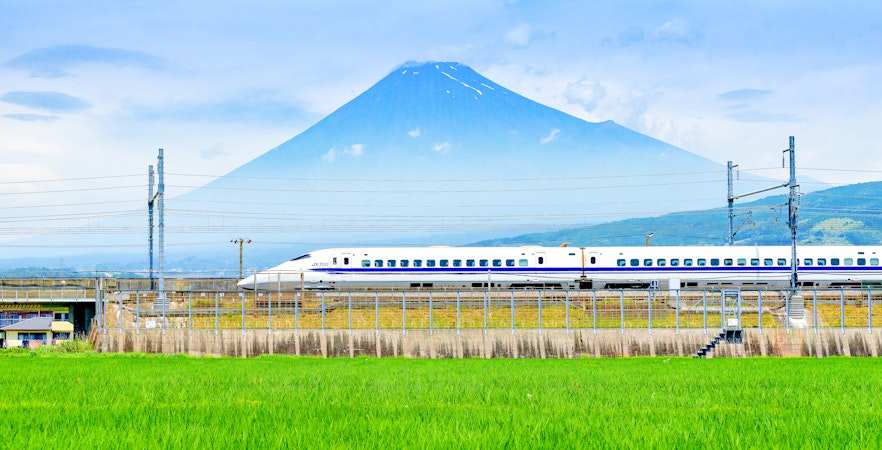Bullet train passing rice fields with Mount Fuji in the background, Fuji City, Shizuoka, Japan.
