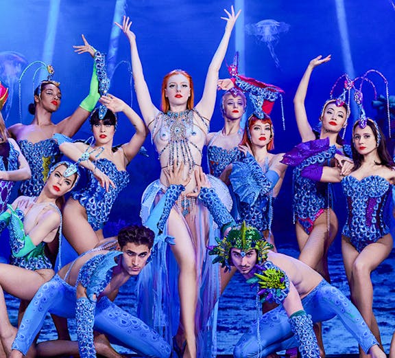 Cabaret performers in vibrant costumes on stage at Paradis Latin, Paris.