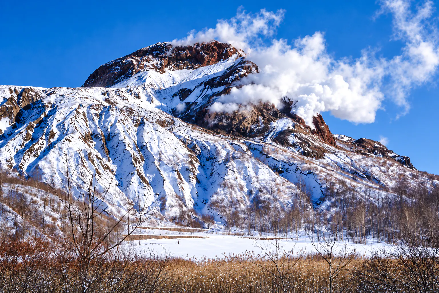 Snow-covered Mount Usu with steam vents in Hokkaido during winter.