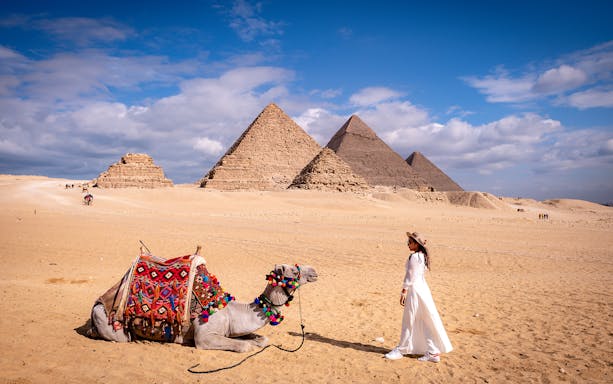 Cairo pyramids with a camel and a person in traditional attire on a private tour.