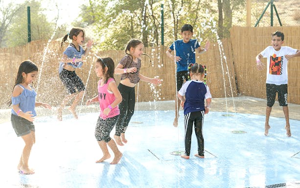 Children playing in water fountains at Aventura Parks rain dance area.