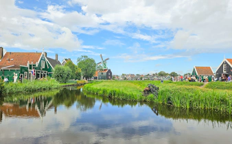 Giethoorn canal with traditional houses and windmill in Zaanse Schans day tour.