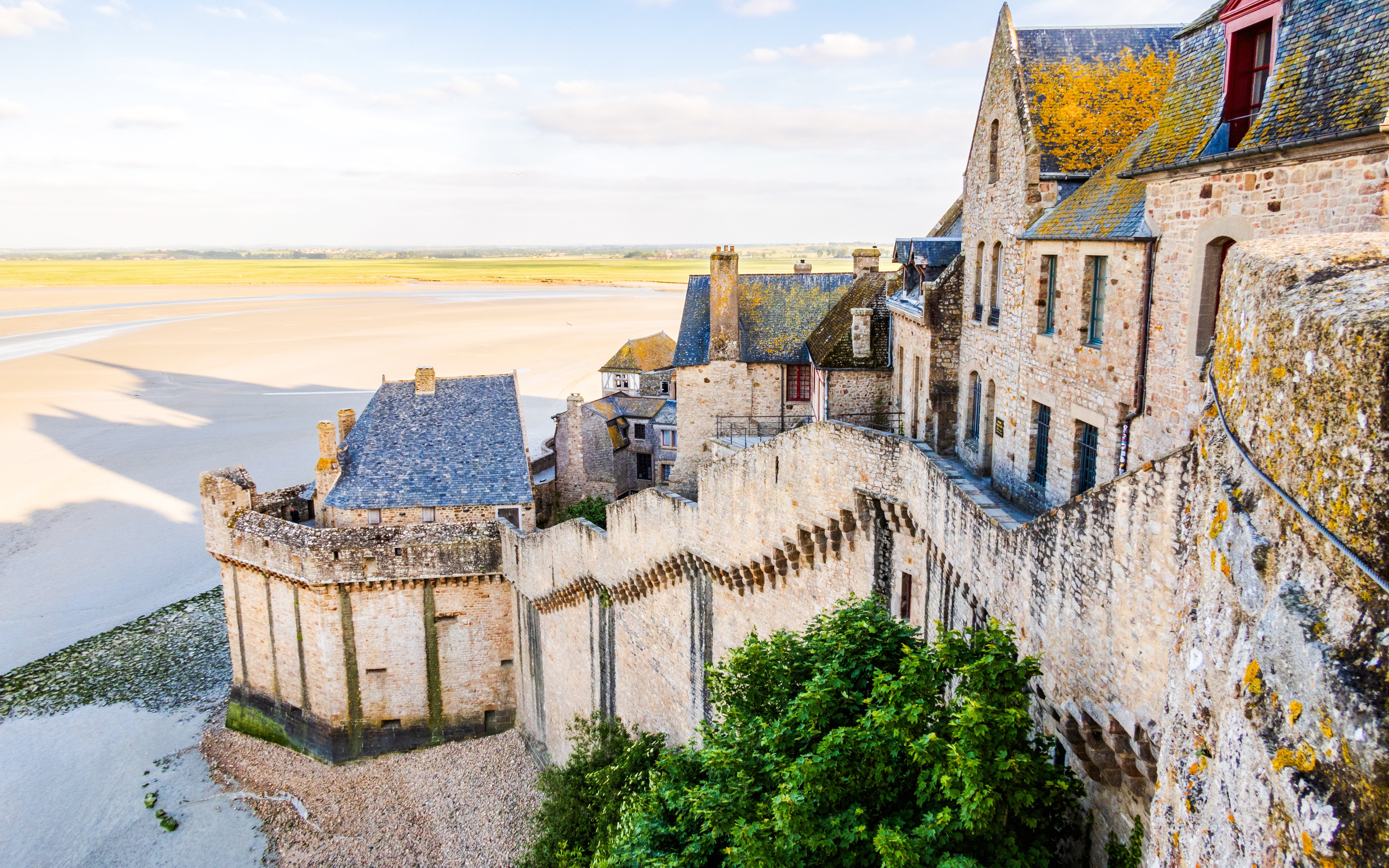 Ramparts of Mont Saint Michel overlooking sandy tidal flats in Normandy, France.