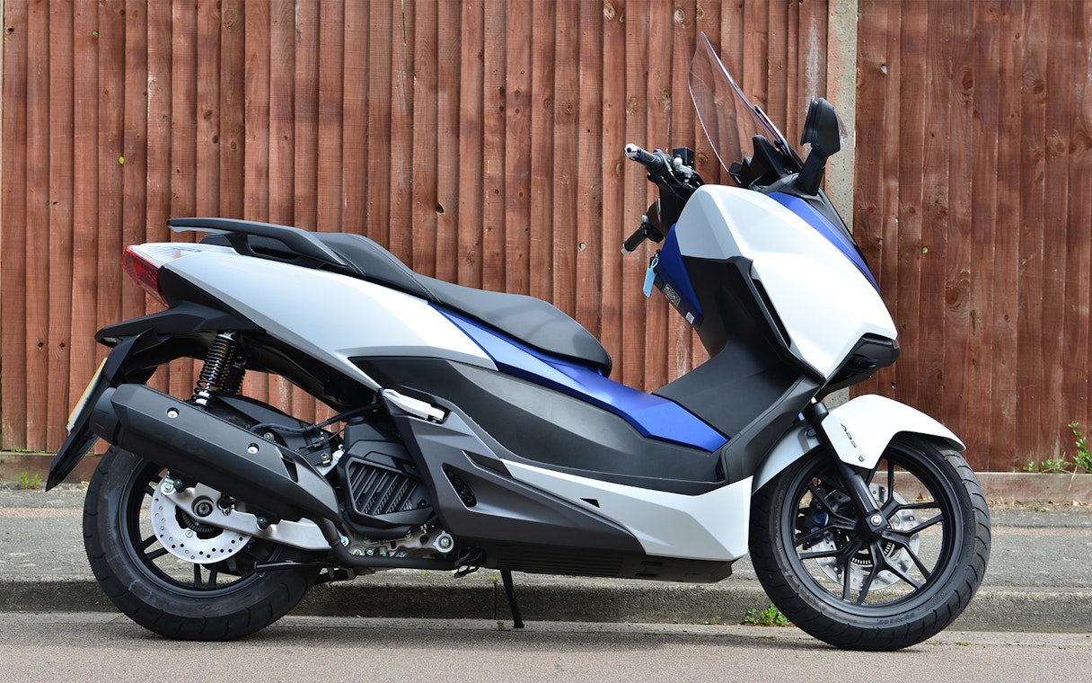Motorbike available for rental in Langkawi, parked against a wooden fence.
