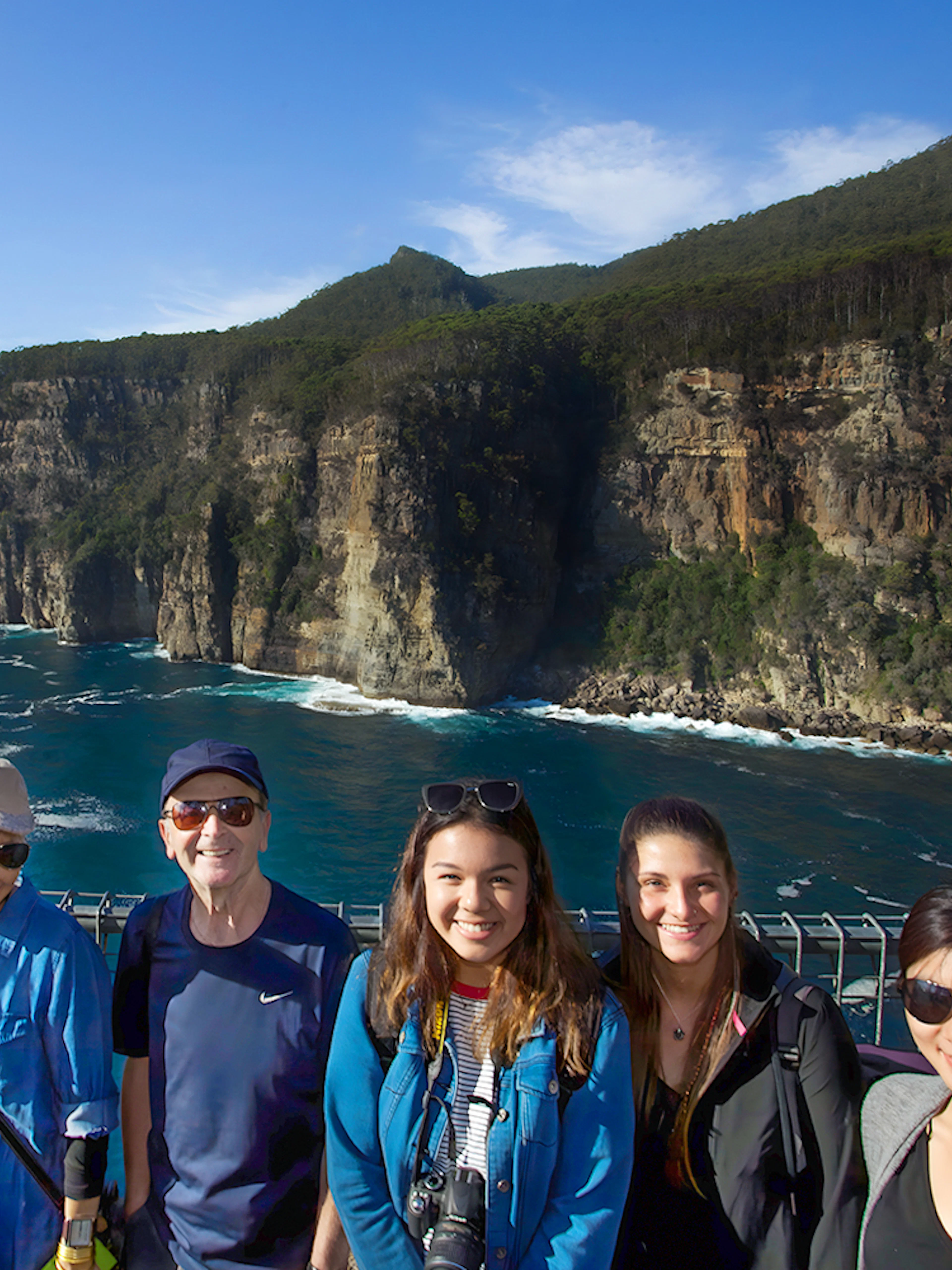 Group of tourists at Tasman Peninsula cliff lookout, Port Arthur, with ocean and cliffs in background.