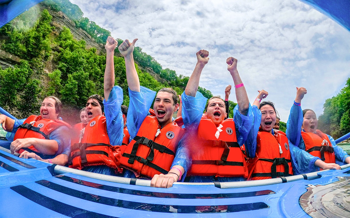 Guests enjoying Whirlpool Jet Boat Tour in Niagara Gorge, Canada, wearing life jackets and cheering.