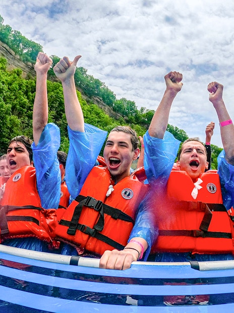 Guests enjoying Whirlpool Jet Boat Tour in Niagara Gorge, Canada, wearing life jackets and cheering.
