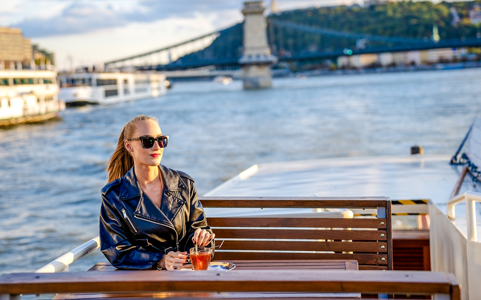 Guest enjoying river view on Elegant Premium Sightseeing Cruise with bridge in background.