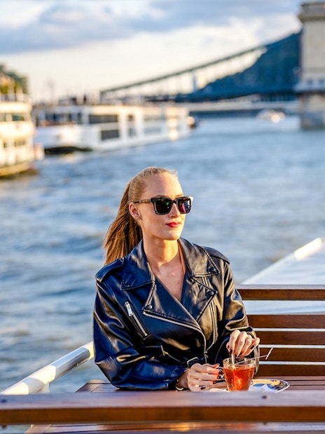 Guest enjoying river view on Elegant Premium Sightseeing Cruise with bridge in background.