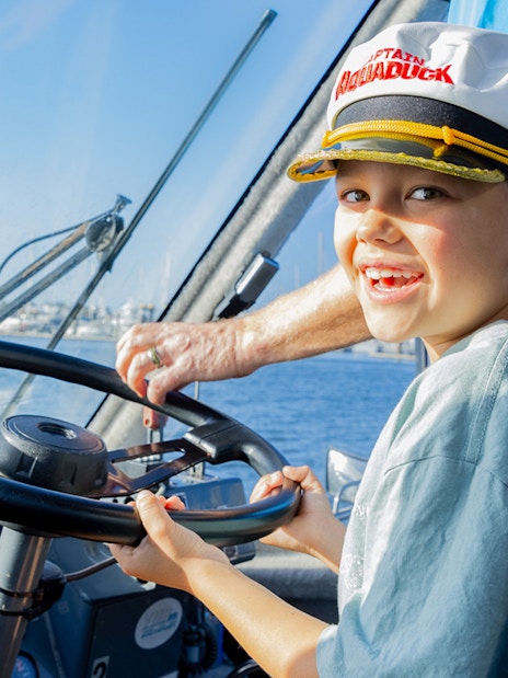Child steering Aquaduck boat during Gold Coast river cruise.