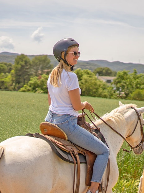 Tourists riding horses on a scenic track, learning to ride in a countryside setting.