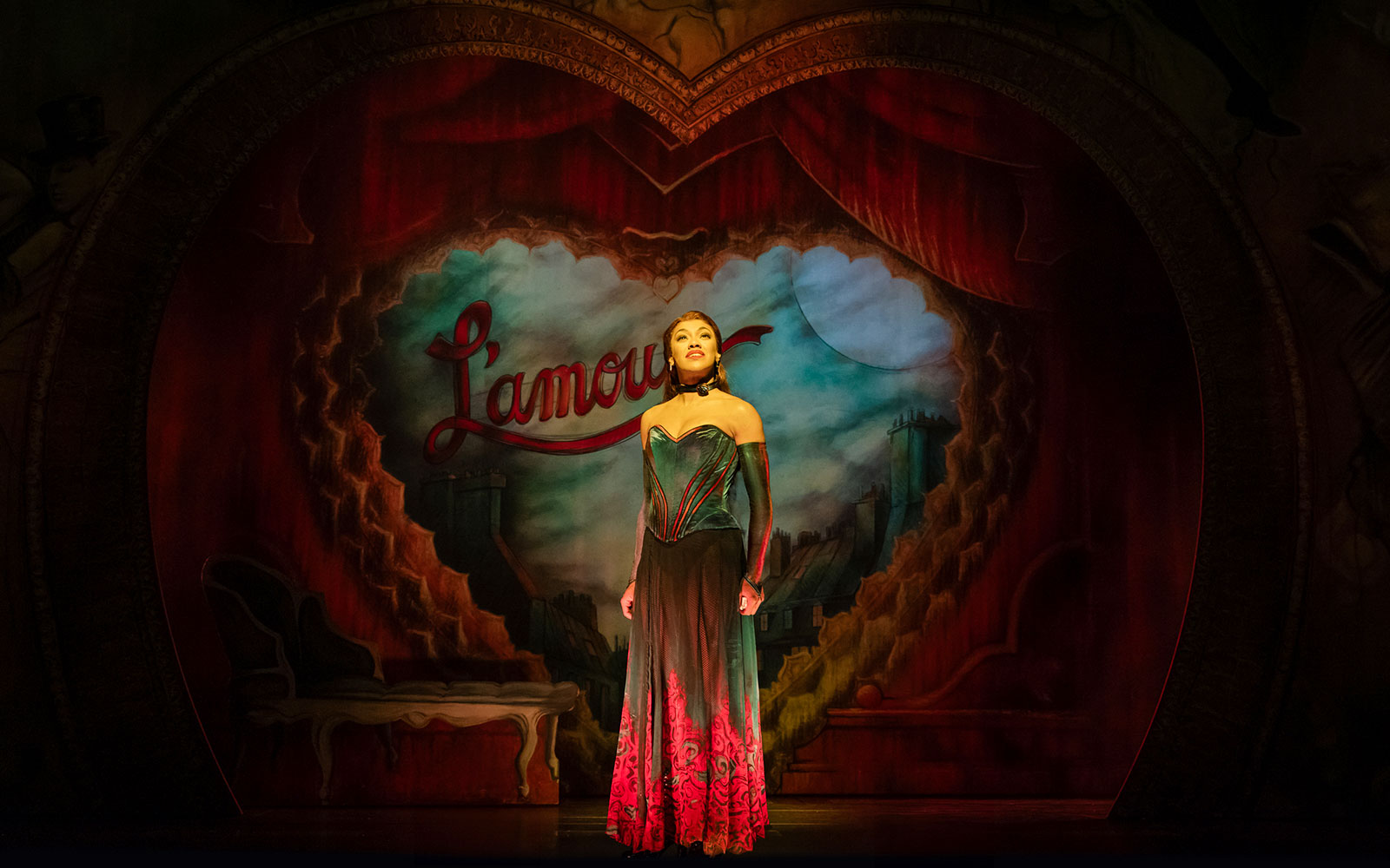 Performer on stage at Moulin Rouge! The Musical, West End, with Parisian backdrop.