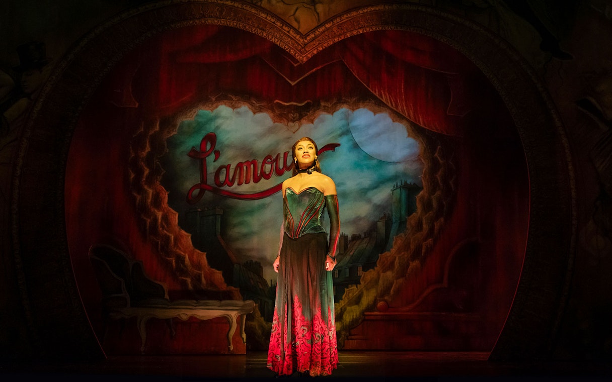 Performer on stage at Moulin Rouge! The Musical, West End, with Parisian backdrop.