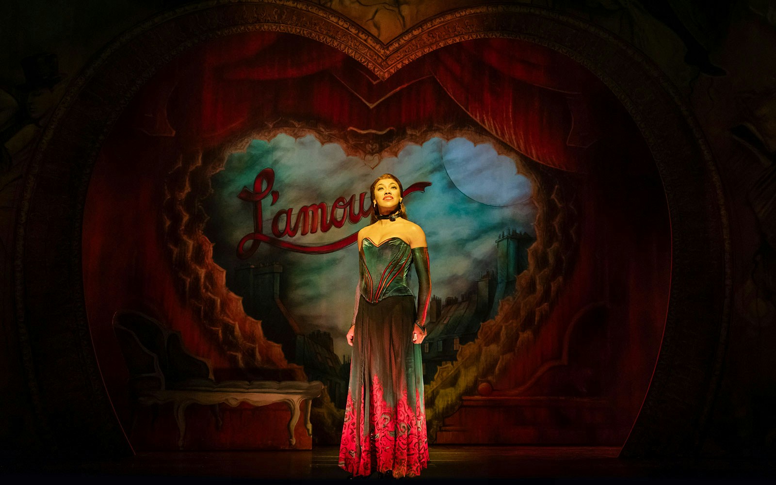 Performer on stage at Moulin Rouge! The Musical, West End, with Parisian backdrop.