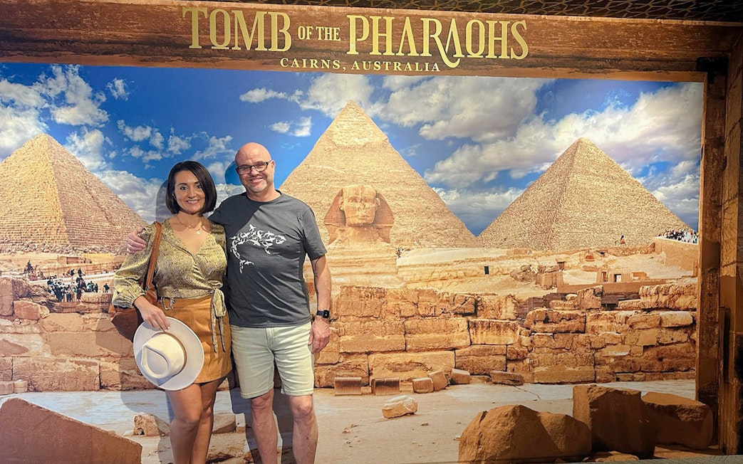 Couple posing in front of Great Pyramids and Sphinx backdrop at Tomb of the Pharaohs exhibit.