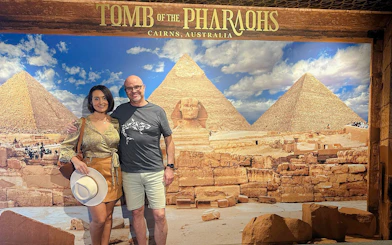 Couple posing in front of Great Pyramids and Sphinx backdrop at Tomb of the Pharaohs exhibit.