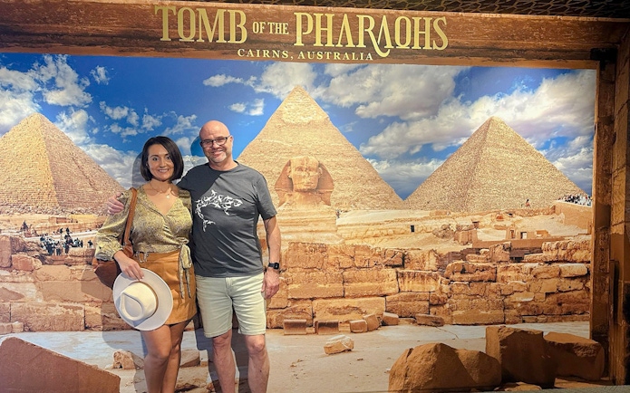Couple posing in front of Great Pyramids and Sphinx backdrop at Tomb of the Pharaohs exhibit.