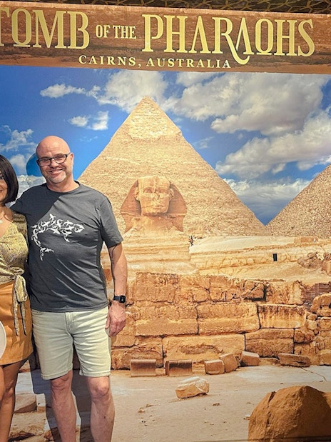 Couple posing in front of Great Pyramids and Sphinx backdrop at Tomb of the Pharaohs exhibit.