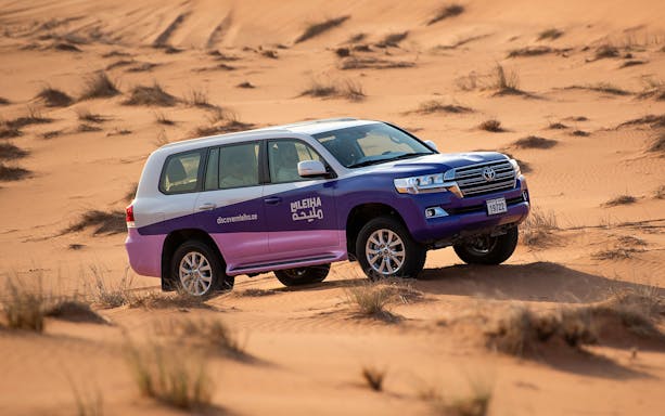 SUV driving through Mleiha desert dunes on a tour to Fossil Rock.