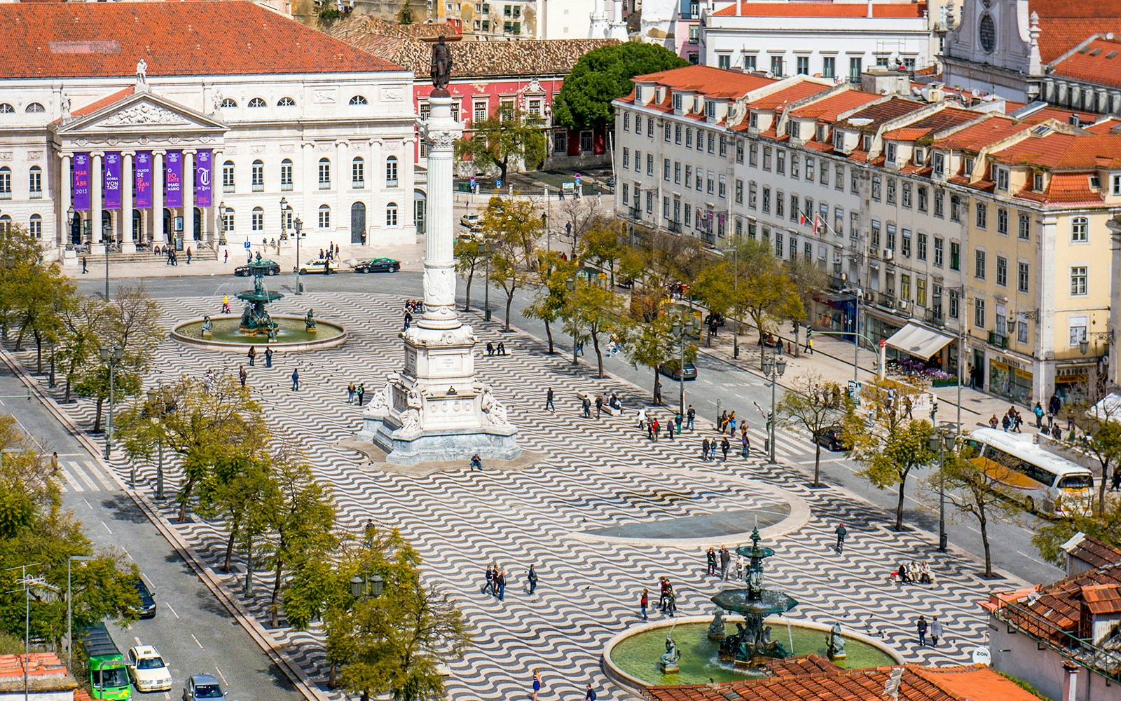 Rossio Square in Lisbon with wavy cobblestone patterns, fountains, and the National Theatre.