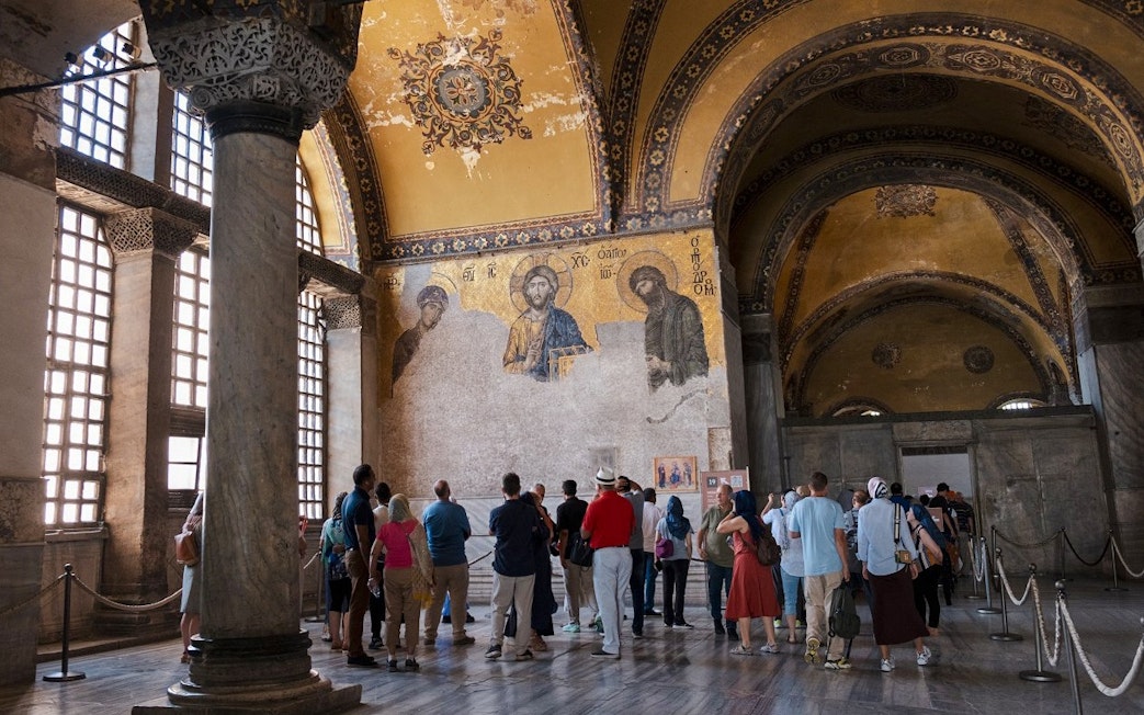 Visitors on a guided tour inside Hagia Sophia, viewing ancient mosaics.