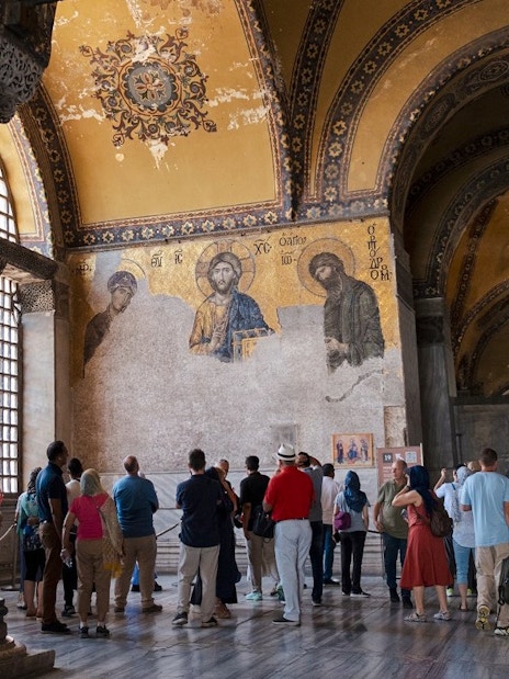 Visitors on a guided tour inside Hagia Sophia, viewing ancient mosaics.
