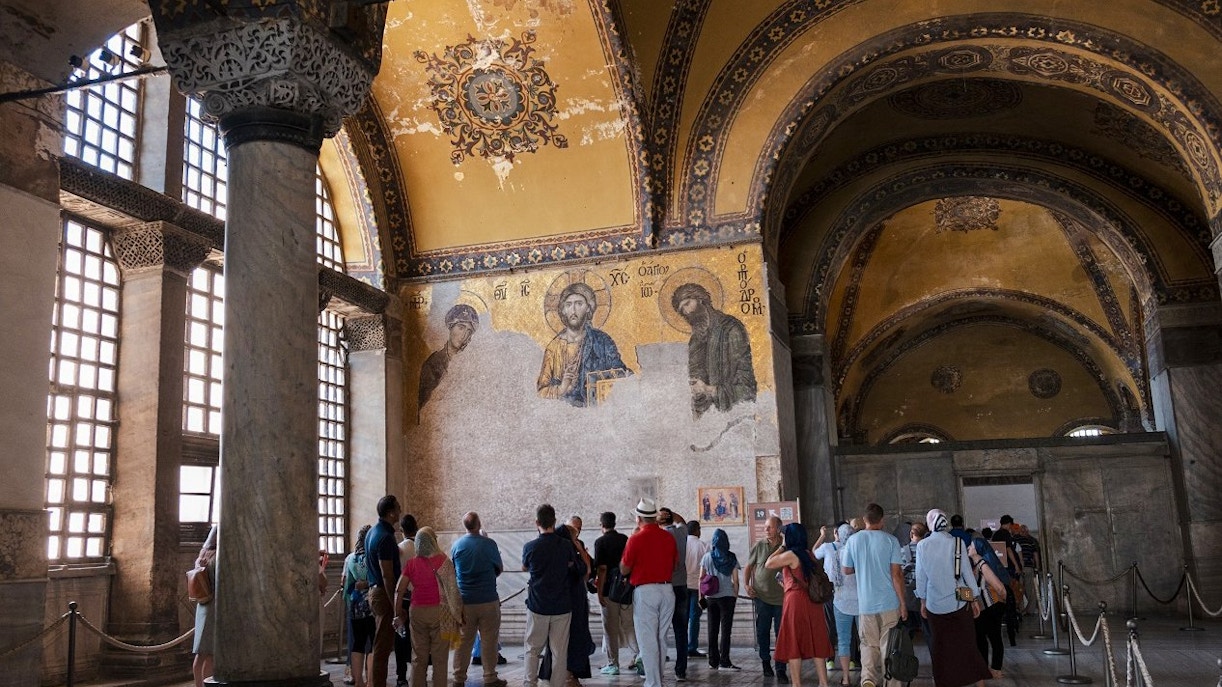 Visitors on a guided tour inside Hagia Sophia, viewing ancient mosaics.