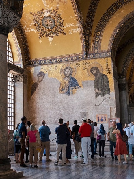 Visitors on a guided tour inside Hagia Sophia, viewing ancient mosaics.