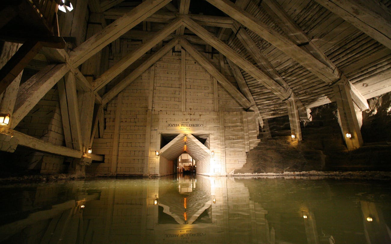 Wieliczka Salt Mine chamber with wooden beams and reflective water surface.