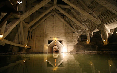 Wieliczka Salt Mine chamber with wooden beams and reflective water surface.