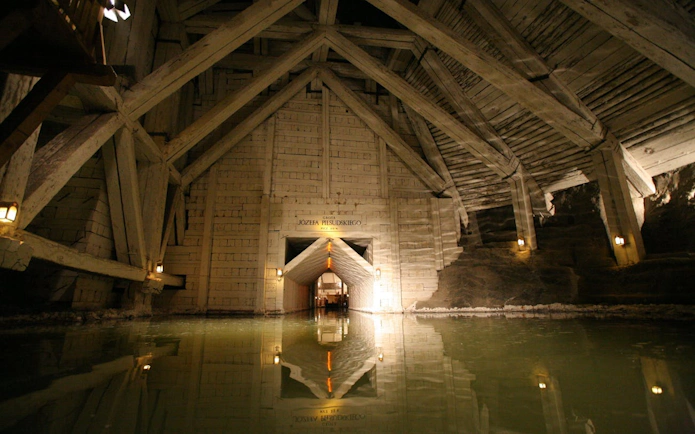 Wieliczka Salt Mine chamber with wooden beams and reflective water surface.