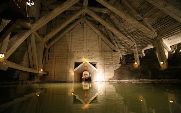 Wieliczka Salt Mine chamber with wooden beams and reflective water surface.
