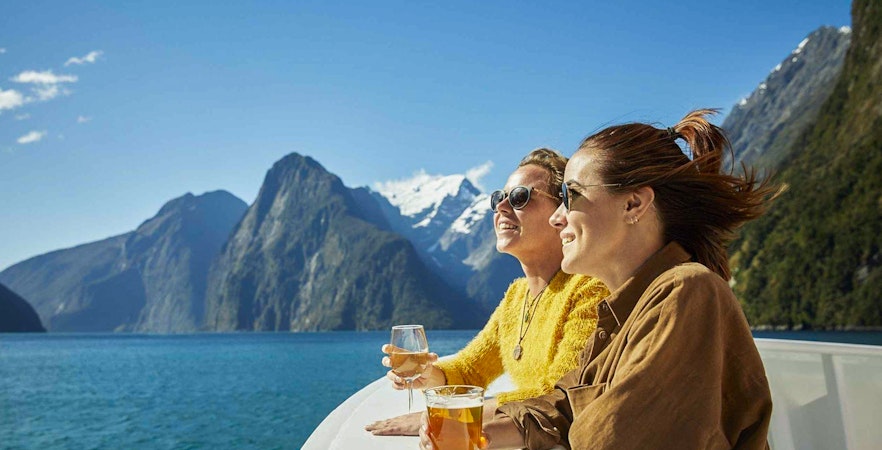 Cruise passengers enjoying drinks with views of Milford Sound fjords.