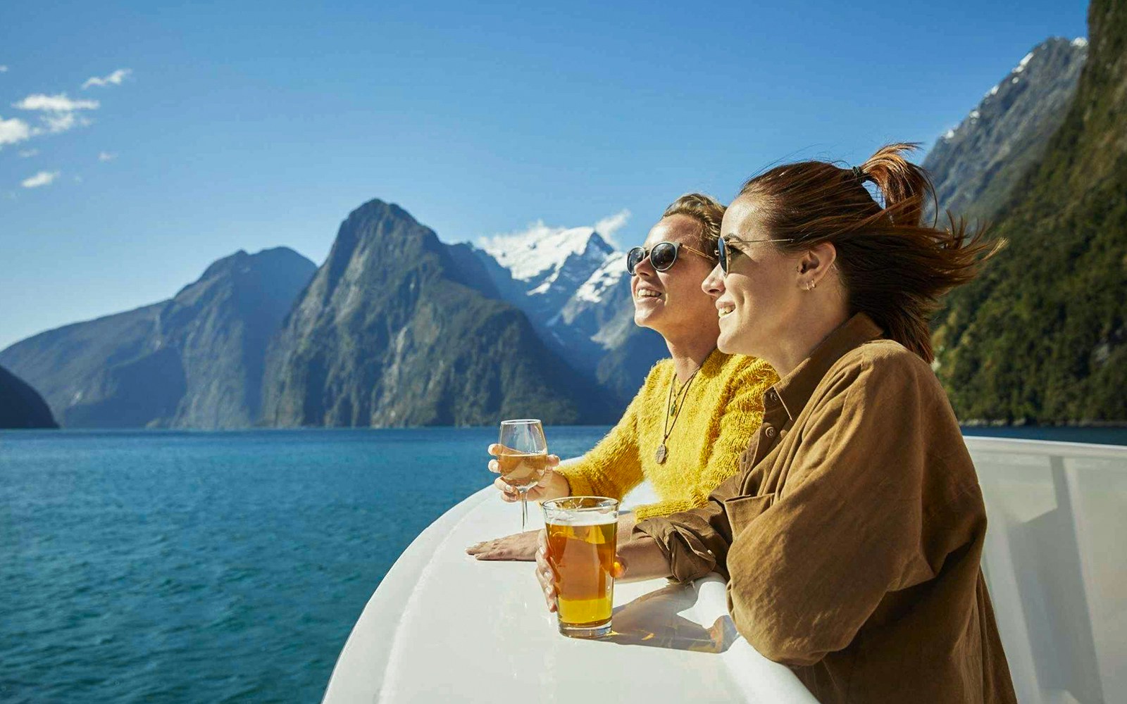 Des touristes profitent d'une croisière haut de gamme dans le Milford Sound avec des canapés gourmands et du champagne au milieu des magnifiques fjords de Nouvelle-Zélande.