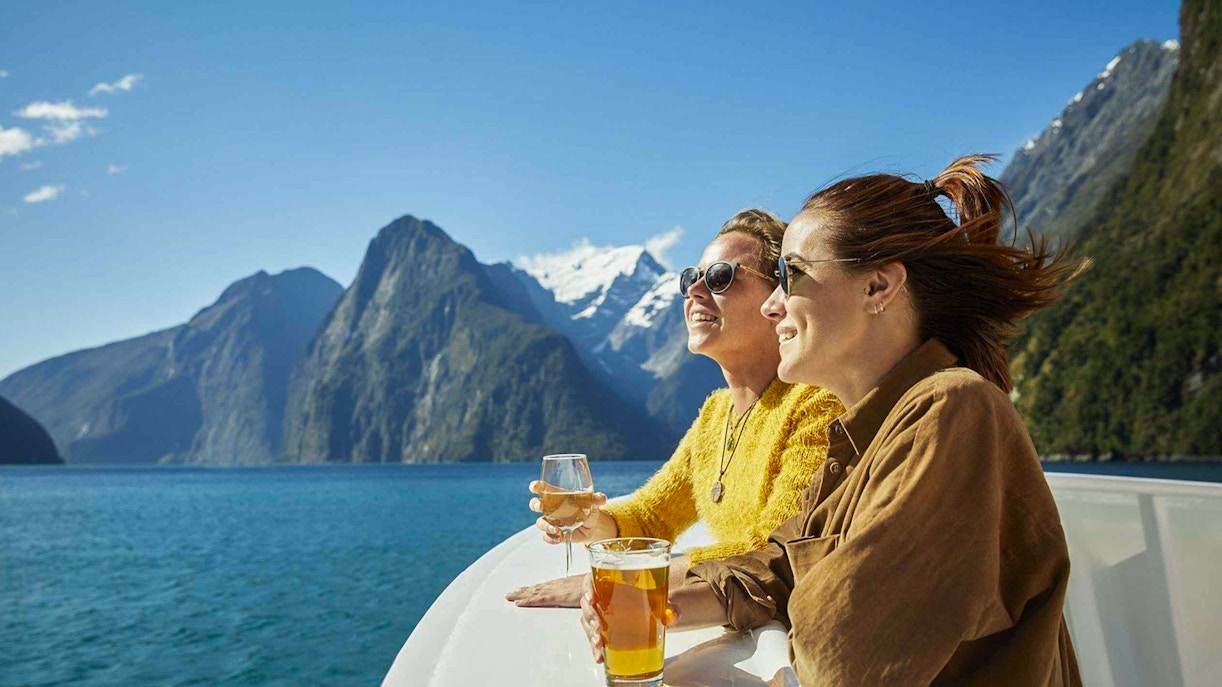 Cruise passengers enjoying drinks with views of Milford Sound fjords.