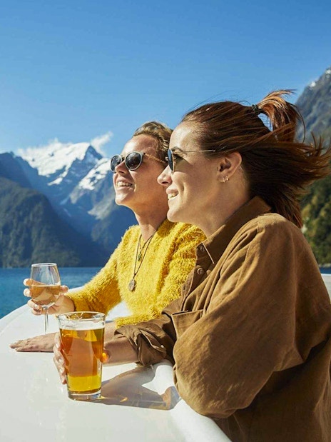 Cruise passengers enjoying drinks with views of Milford Sound fjords.