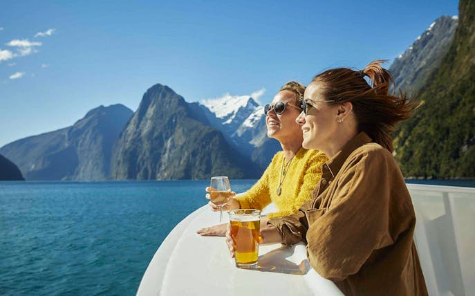 Cruise passengers enjoying drinks with views of Milford Sound fjords.